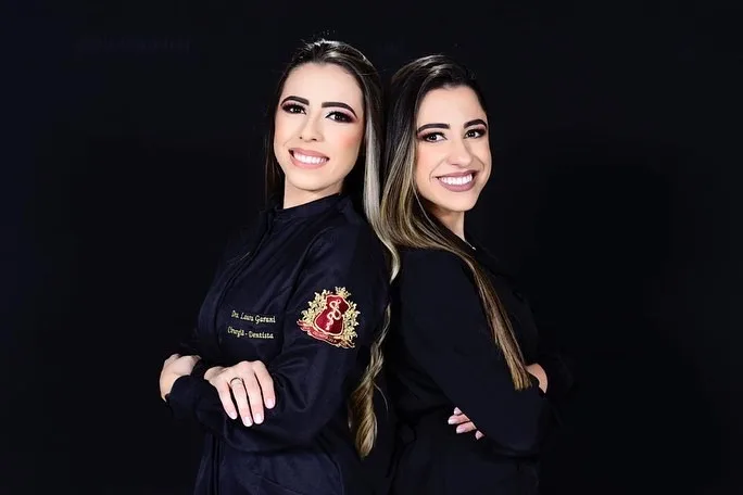 Dra. Taís Garani com colega, ambas de jaleco escuro